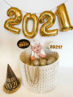 a baby is sitting in a basket with balloons