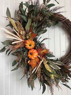 a wreath with orange flowers and green leaves hanging on a door handle, decorated with greenery