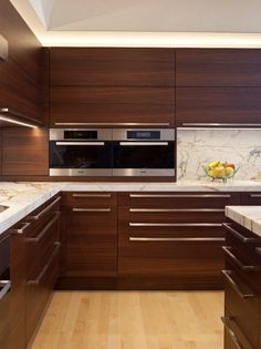 a modern kitchen with wood cabinets and marble counter tops, along with wooden flooring