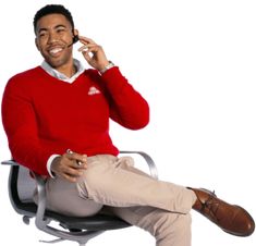 a man sitting in an office chair talking on a cell phone and smiling at the camera