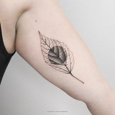 a woman's arm with a leaf tattoo on it