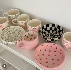 many cups and bowls are sitting on a shelf next to each other in different designs