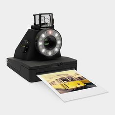 an old fashioned camera sitting on top of a white table next to a polaroid print