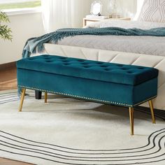 a blue bench sitting on top of a rug in front of a bed with white sheets