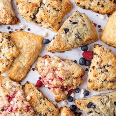 several different types of pastries on a white surface with blueberries and raspberries