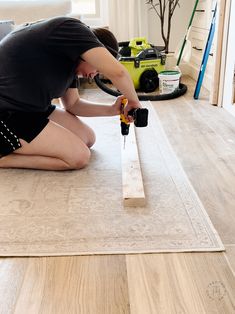 a woman kneeling on the floor with a drill