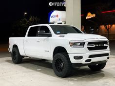 a white ram truck parked in front of a gas station at night with its lights on