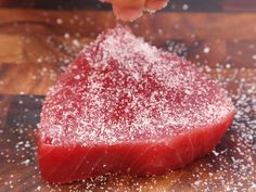 someone is sprinkling sugar on a piece of meat