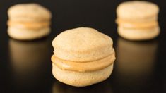 three macaroni and cheese sandwich cookies on a black surface with one cookie in the foreground