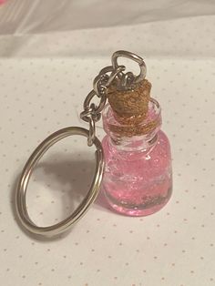 a pink bottle with a corked keychain is sitting on a table