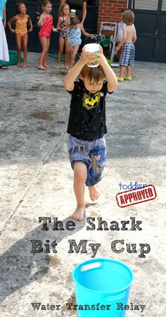 a little boy that is standing in the sand with a bucket and some people behind him