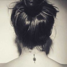 the back of a woman's neck with a small diamond tattoo on her left shoulder