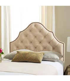 a white bed with a beige headboard and two pillows on it's sides