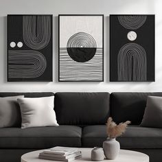 three black and white paintings hang on the wall above a gray couch in a modern living room