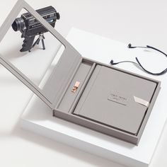 an open box with a camera inside on a white surface next to a pair of glasses