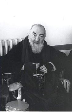 an old black and white photo of a man with a long beard sitting on a chair