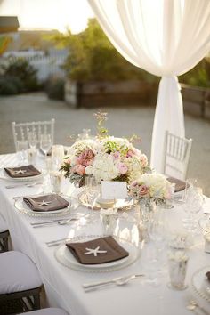 the table is set with white linens and flowers