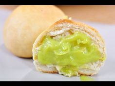 there is a sandwich with guacamole on it next to a roll that has been cut in half