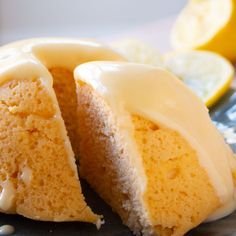 there is a piece of cake with icing on the plate next to lemons