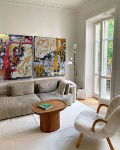 a living room filled with furniture and paintings on the wall