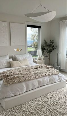 a large white bed sitting in a bedroom next to a window with lots of windows