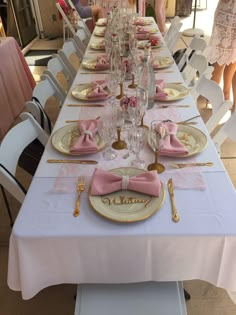 a long table with pink and gold place settings