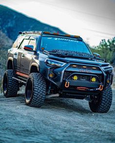 the front end of a gray truck on a dirt road