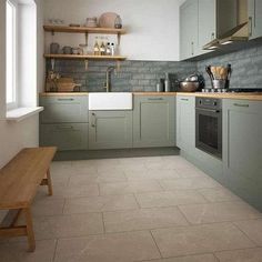 a kitchen with grey cabinets and white counter tops, wooden bench in front of the sink