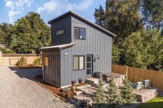 a small gray house sitting in the middle of a yard