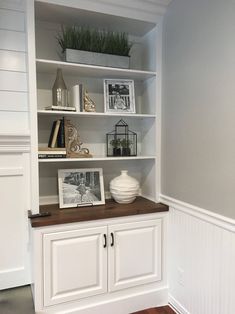 a white bookcase with some pictures and other items on it in a room that has wood flooring