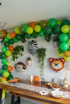 a party table with balloons and jungle decorations