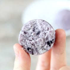 a close up of a person holding a blueberry muffin in their left hand