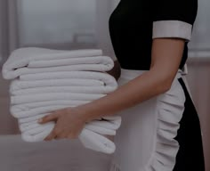 a woman holding a stack of white towels