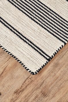 an area rug with black and white stripes on the wood floor in front of it