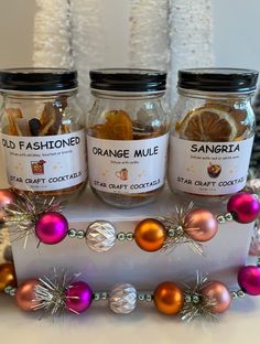 three glass jars filled with oranges and other holiday decorations on top of a table