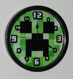 a green and black clock with numbers on it's face is hanging from the wall