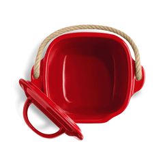 a red bowl with a rope handle and lid next to a pair of scissors on a white background