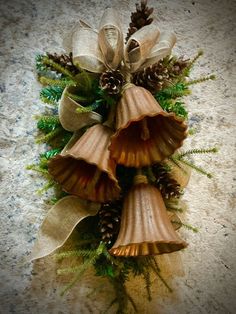 three bell shaped flowers with pine cones and evergreens on the top, hanging from a stone wall