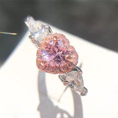 a pink diamond ring sitting on top of a table