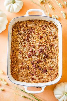 a casserole dish filled with oatmeal and pecans on an orange surface