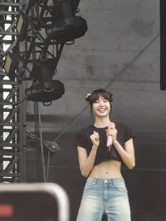 a woman standing on stage holding a microphone in her right hand and smiling at the camera