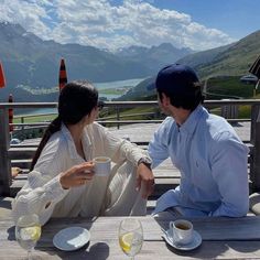 a man and woman sitting at a table with cups of coffee in front of them