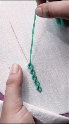 someone is stitching something on a piece of fabric with green thread and scissors in the background