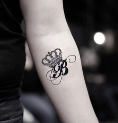 a black and white photo of a woman's arm with a crown tattoo on it