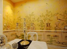 a dining room with yellow walls and floral wallpaper on the walls, along with white chairs