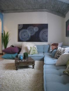 a living room filled with lots of furniture and pillows on top of a white rug