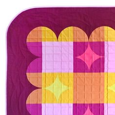 a close up of a quilt on a white surface with pink and yellow squares in the center