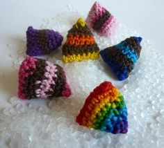 small crocheted hats sitting on top of a white table covered in lots of beads