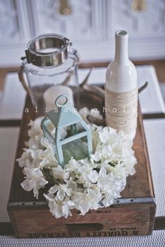 a tray with flowers and a bottle on it sitting on top of a wooden table