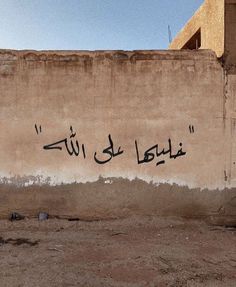 graffiti written on the side of a building in arabic writing is seen against a blue sky